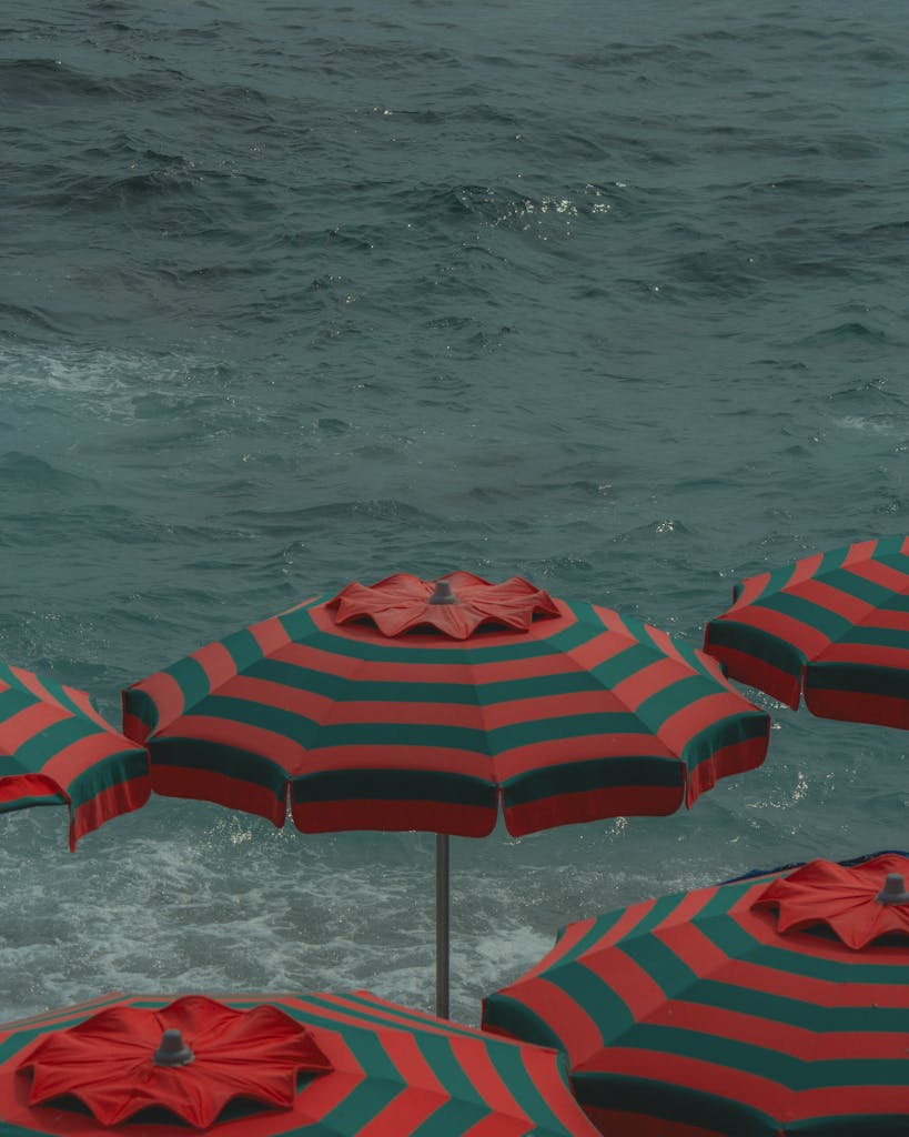 Striped umbrellas on a serene beach in Monterosso al Mare, Italy, capturing vibrant coastal vibes.